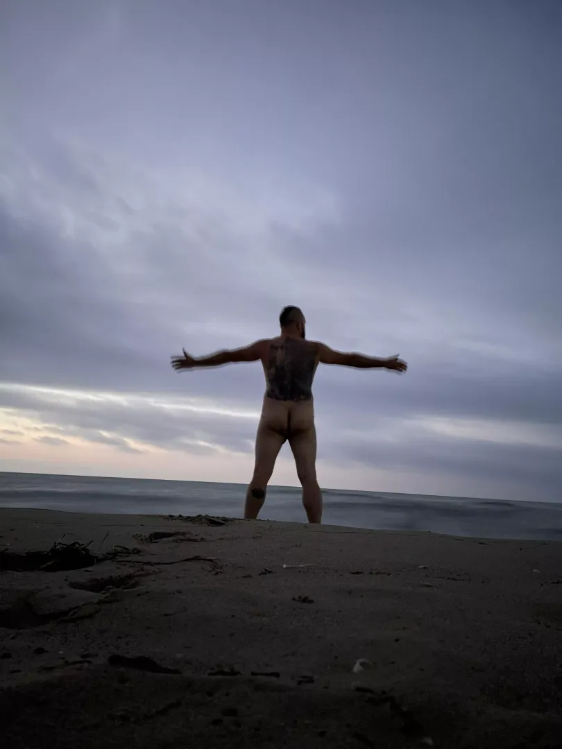 Bad inked and naked man at the beach.